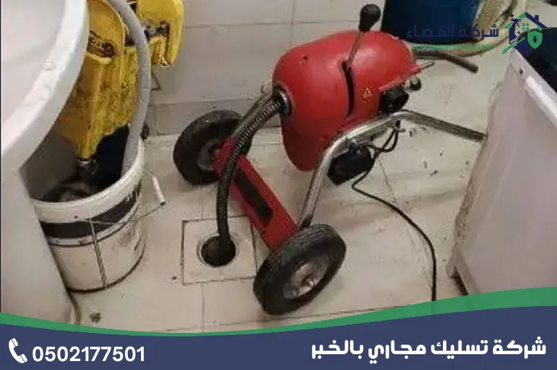 تسليك مجاري الحمام بالخبر: جهاز تسليك كهربائي أحمر عند بالوعة أرضية داخل حمام